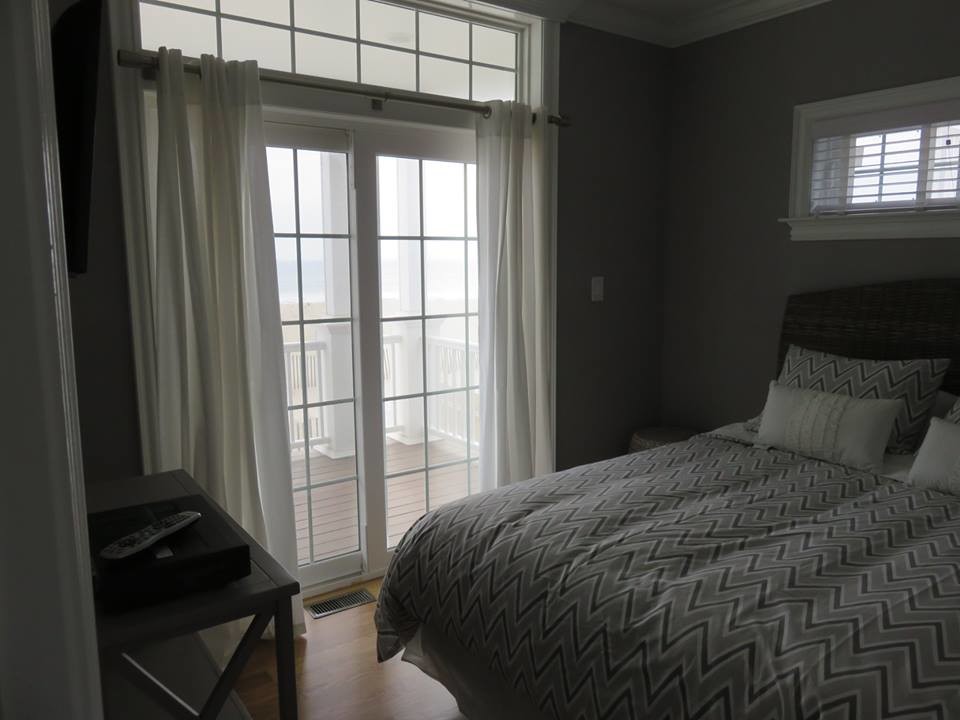 Foto de dormitorio principal costero de tamaño medio sin chimenea con paredes grises y suelo de madera en tonos medios