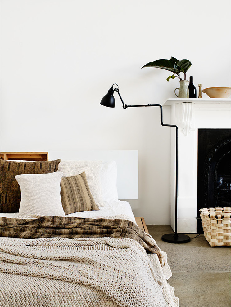 Idée de décoration pour une grande chambre minimaliste avec un mur blanc, sol en béton ciré, une cheminée standard et un manteau de cheminée en bois.