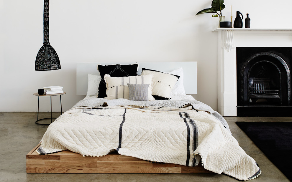 Inspiration pour une grande chambre mansardée ou avec mezzanine minimaliste avec un mur blanc, sol en béton ciré, une cheminée standard et un manteau de cheminée en bois.