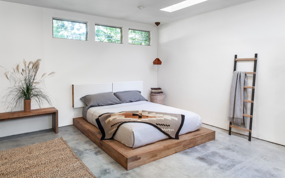 Imagen de dormitorio principal contemporáneo grande sin chimenea con paredes blancas y suelo de cemento