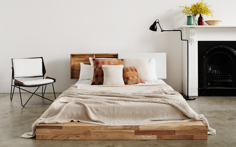 Idee per una grande camera da letto moderna con pareti bianche, pavimento in cemento, camino classico e cornice del camino in legno