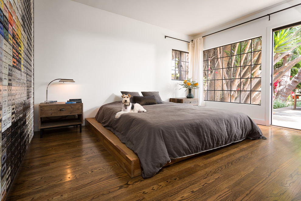 Cette image montre une chambre parentale minimaliste de taille moyenne avec un mur blanc et un sol en bois brun.