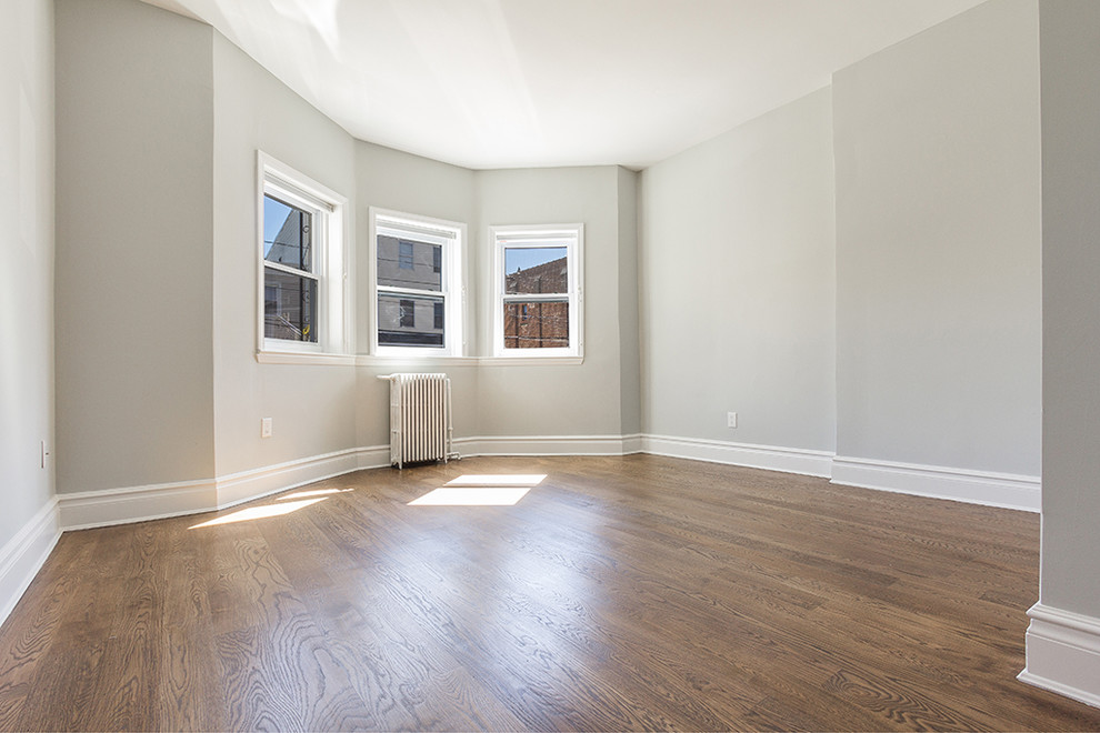 Kleines Klassisches Gästezimmer ohne Kamin mit grauer Wandfarbe, braunem Holzboden und braunem Boden in New York
