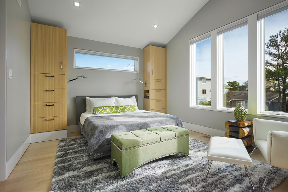Diseño de dormitorio principal contemporáneo grande con paredes grises, suelo de madera clara y chimenea lineal