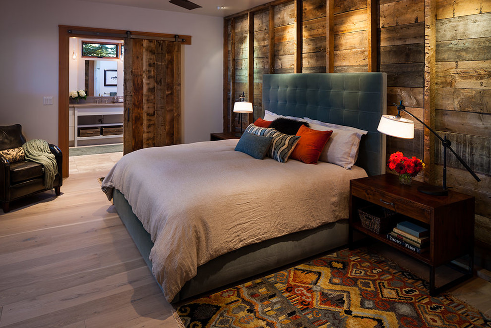 Ejemplo de dormitorio principal rústico de tamaño medio sin chimenea con paredes blancas y suelo de madera clara