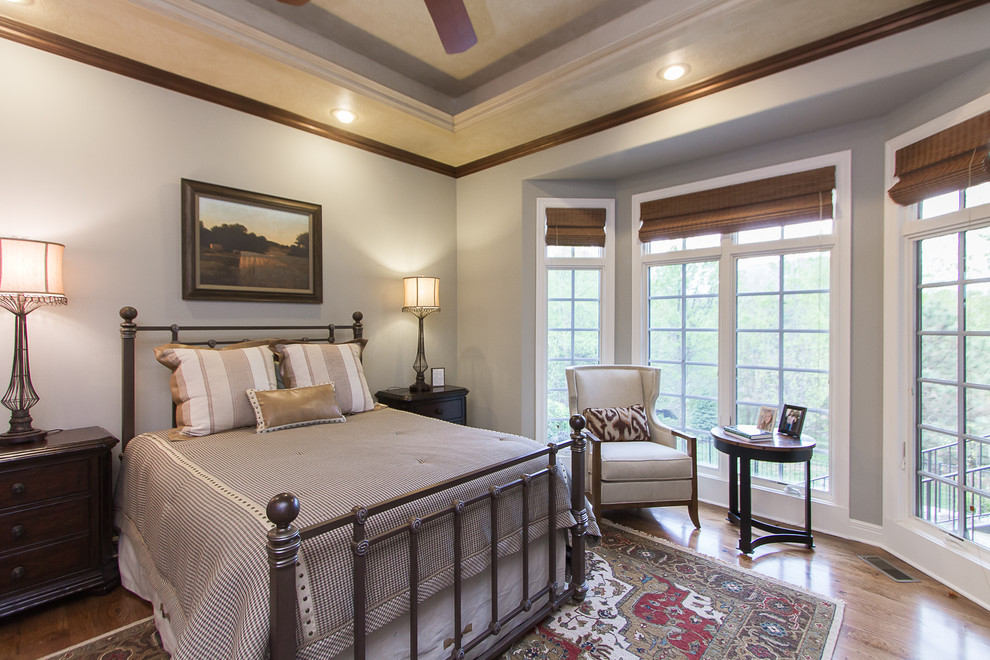 На фото: большая хозяйская спальня в стиле рустика с серыми стенами, паркетным полом среднего тона, стандартным камином, фасадом камина из плитки и коричневым полом с