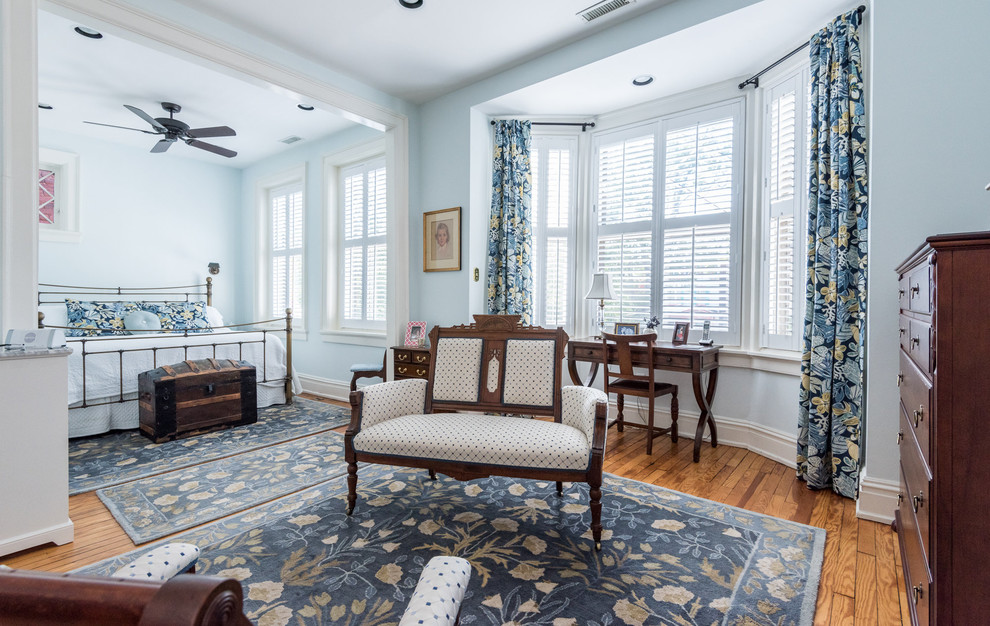 Großes Klassisches Hauptschlafzimmer mit blauer Wandfarbe, hellem Holzboden, braunem Boden, Kamin und Kaminumrandung aus Stein in Richmond