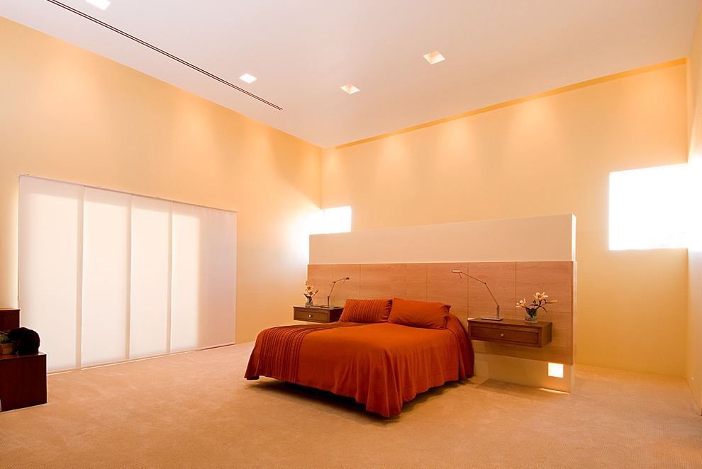 Bild på ett mycket stort funkis huvudsovrum, med orange väggar, heltäckningsmatta och beiget golv