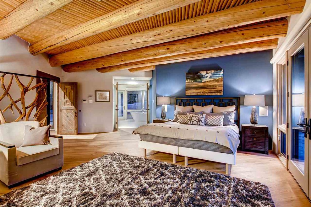 Foto på ett stort amerikanskt sovrum, med blå väggar och mellanmörkt trägolv