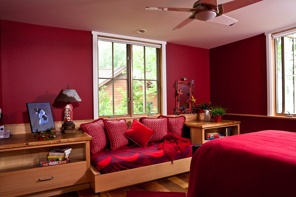 Modelo de habitación de invitados contemporánea de tamaño medio sin chimenea con paredes rojas y suelo de madera en tonos medios