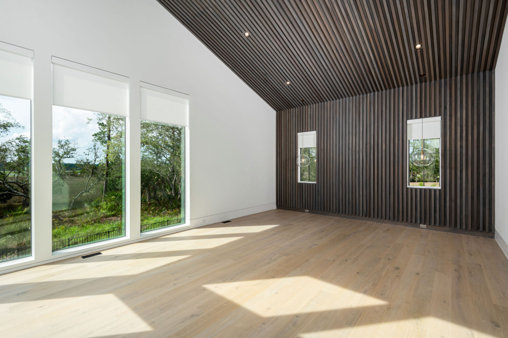 Geräumiges Modernes Hauptschlafzimmer mit bunten Wänden, hellem Holzboden, beigem Boden, Holzdecke und Holzwänden in Charleston