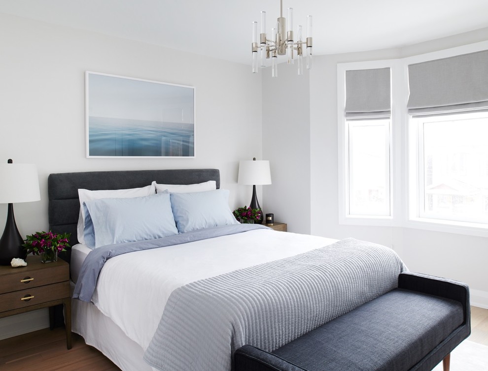 Imagen de habitación de invitados actual de tamaño medio sin chimenea con paredes grises, suelo de madera clara y suelo beige