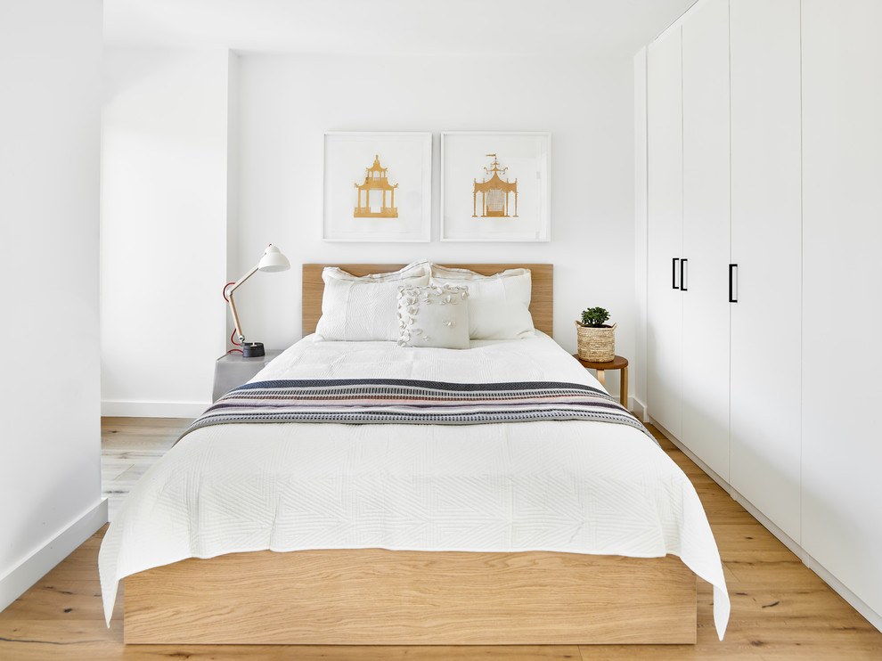 Cette image montre une petite chambre parentale design avec un mur blanc, un sol marron et un sol en bois brun.