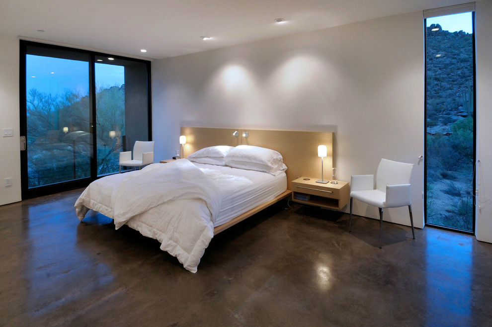 Inspiration pour une chambre design avec sol en béton ciré et un mur blanc.