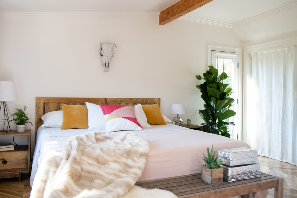 Modelo de dormitorio principal bohemio de tamaño medio con paredes blancas y suelo de madera en tonos medios