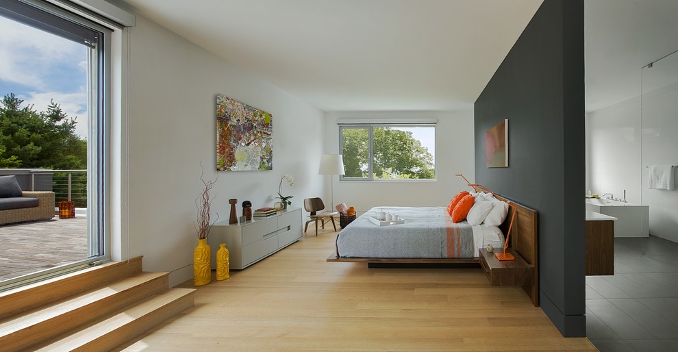 Modern inredning av ett stort huvudsovrum, med grå väggar, mellanmörkt trägolv och beiget golv