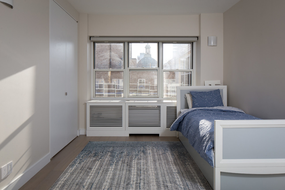 Ejemplo de habitación de invitados actual de tamaño medio sin chimenea con paredes beige, suelo de madera clara y suelo marrón