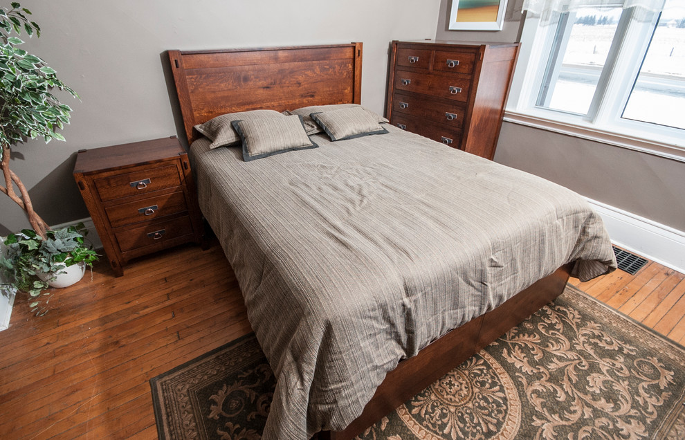 Modelo de dormitorio rústico de tamaño medio con paredes grises y suelo de madera en tonos medios