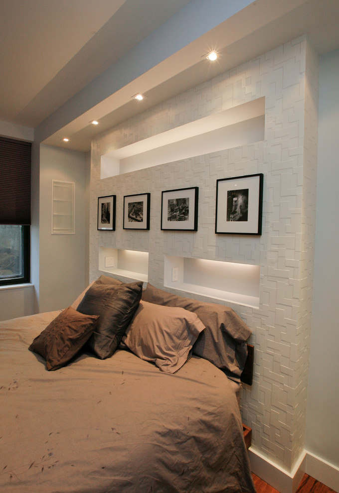 This is an example of a medium sized contemporary master bedroom in New York with white walls and light hardwood flooring.