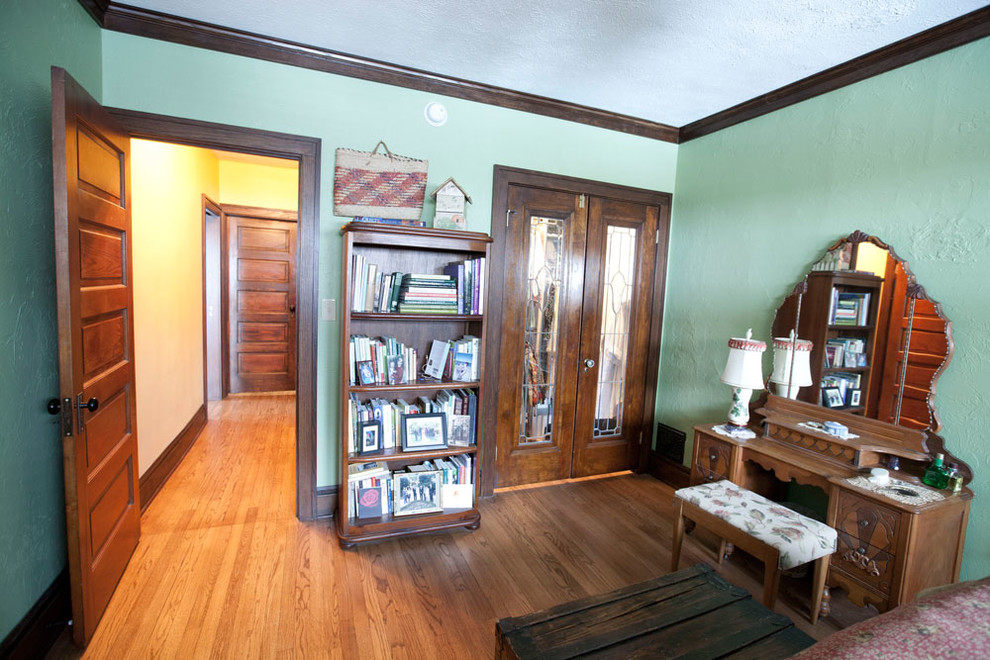 Imagen de habitación de invitados de estilo americano de tamaño medio sin chimenea con paredes verdes, suelo de madera clara y suelo marrón