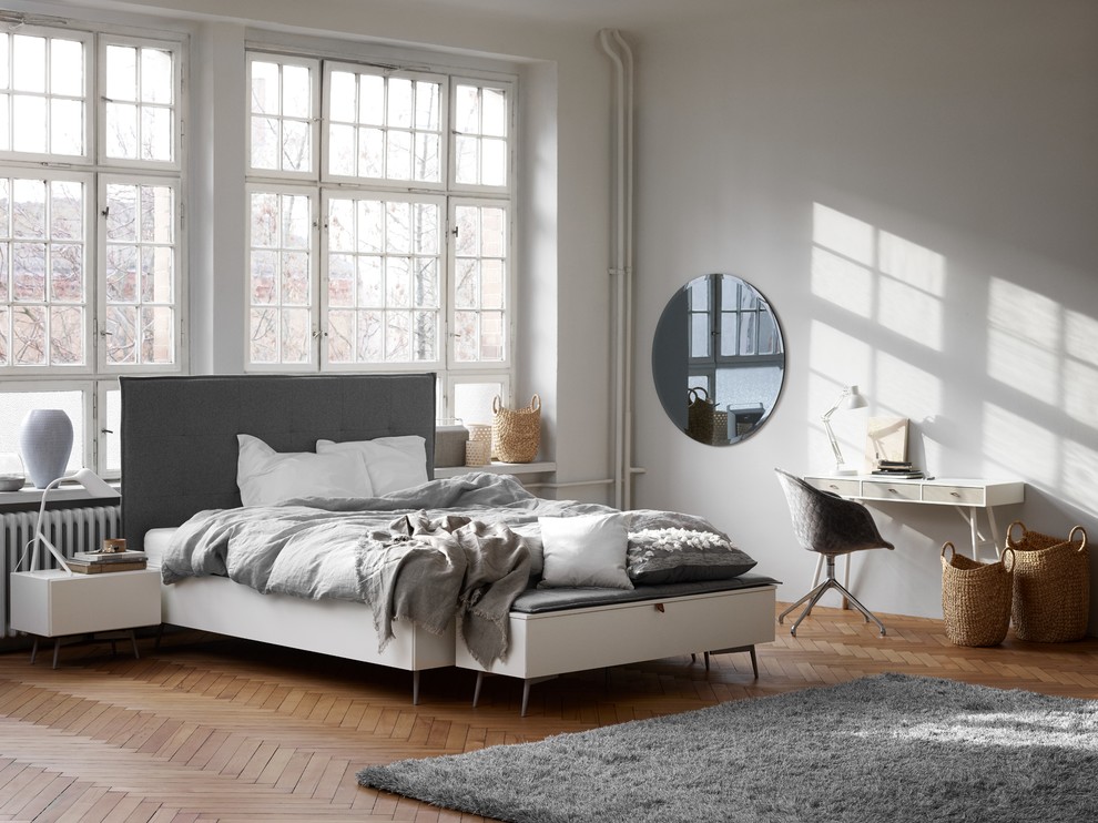 Example of a mid-sized trendy master light wood floor bedroom design in Manchester with white walls