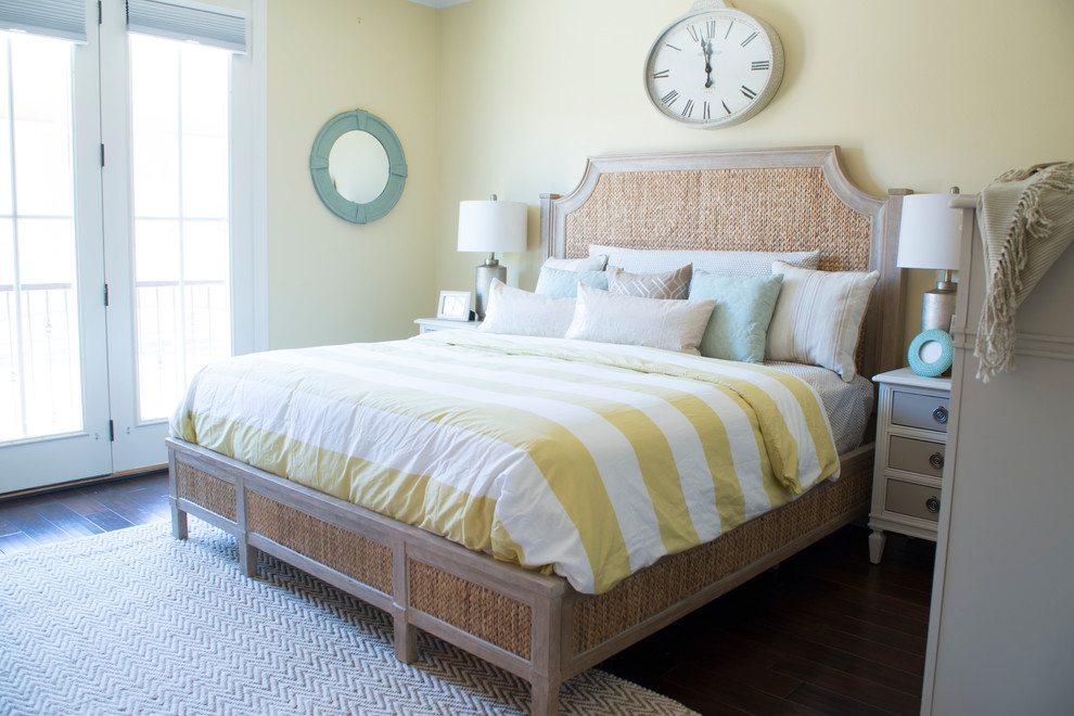 Ejemplo de dormitorio principal costero de tamaño medio con paredes amarillas y suelo de madera oscura