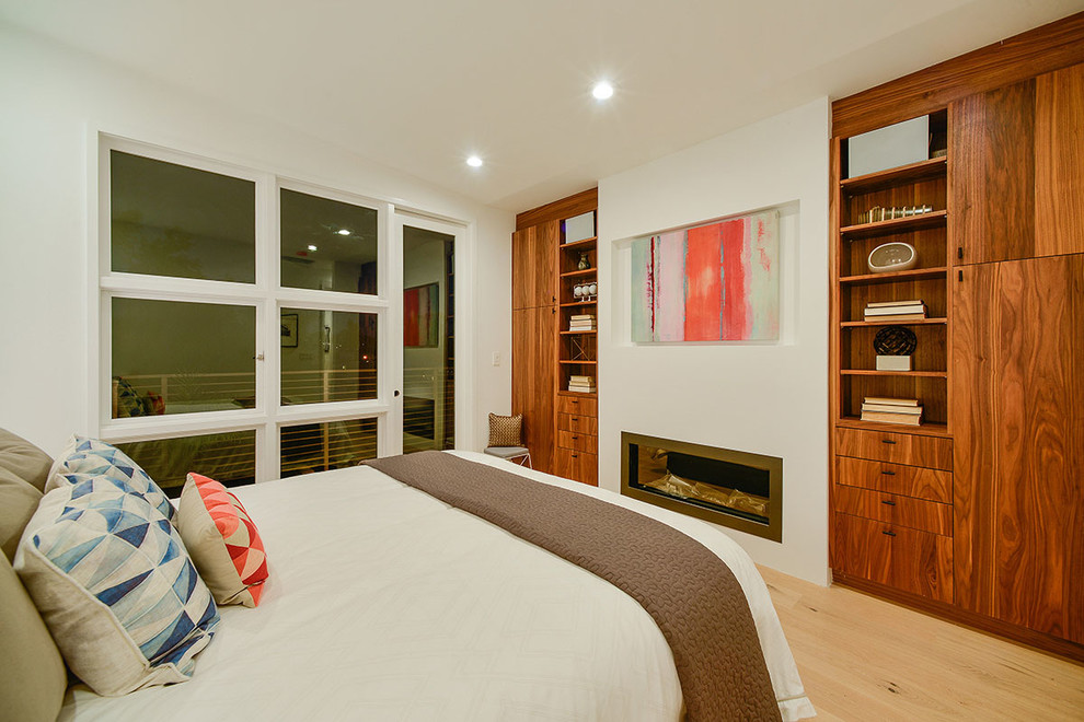 サンフランシスコにある中くらいなコンテンポラリースタイルのおしゃれな主寝室 (淡色無垢フローリング、白い壁、横長型暖炉、漆喰の暖炉まわり、茶色い床) のインテリア