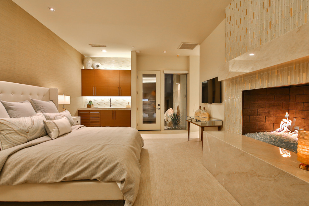 Immagine di una grande camera degli ospiti design con pareti beige, moquette, camino classico, cornice del camino piastrellata e pavimento beige