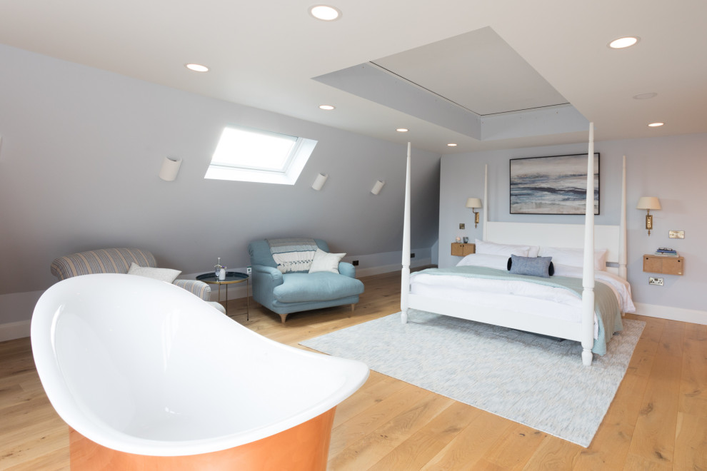 Imagen de dormitorio principal y abovedado actual extra grande sin chimenea con paredes azules, suelo de madera clara y suelo marrón