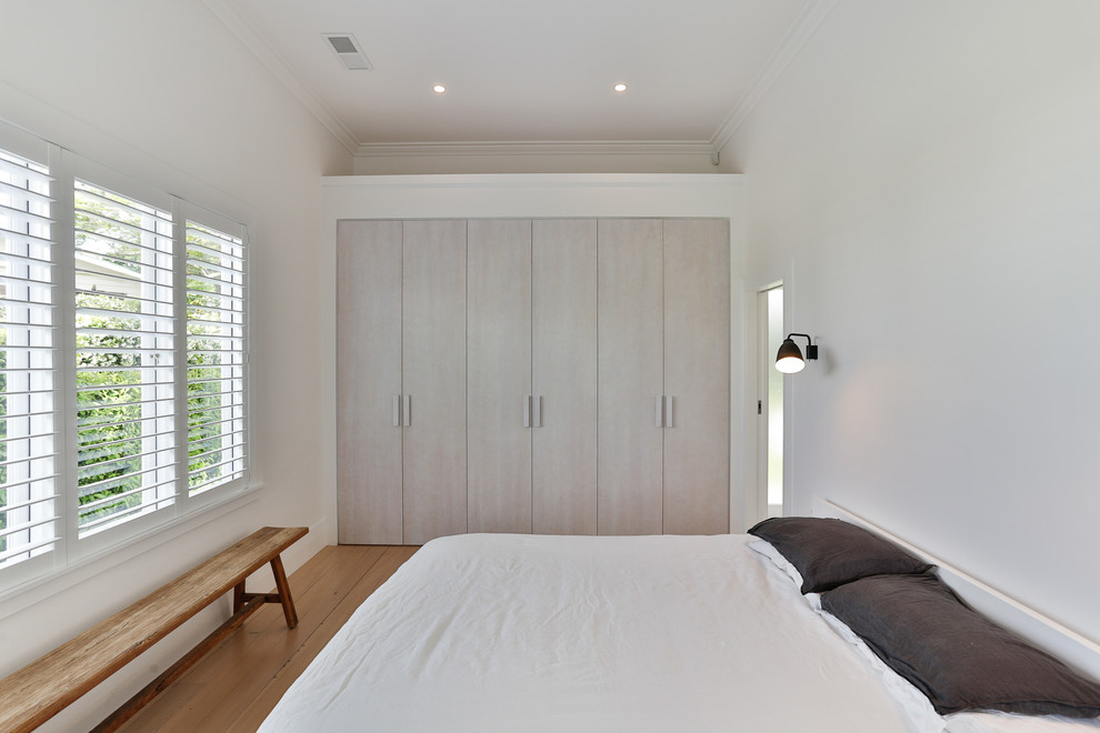 Inspiration for a mid-sized timeless master light wood floor and brown floor bedroom remodel in Auckland with white walls and no fireplace