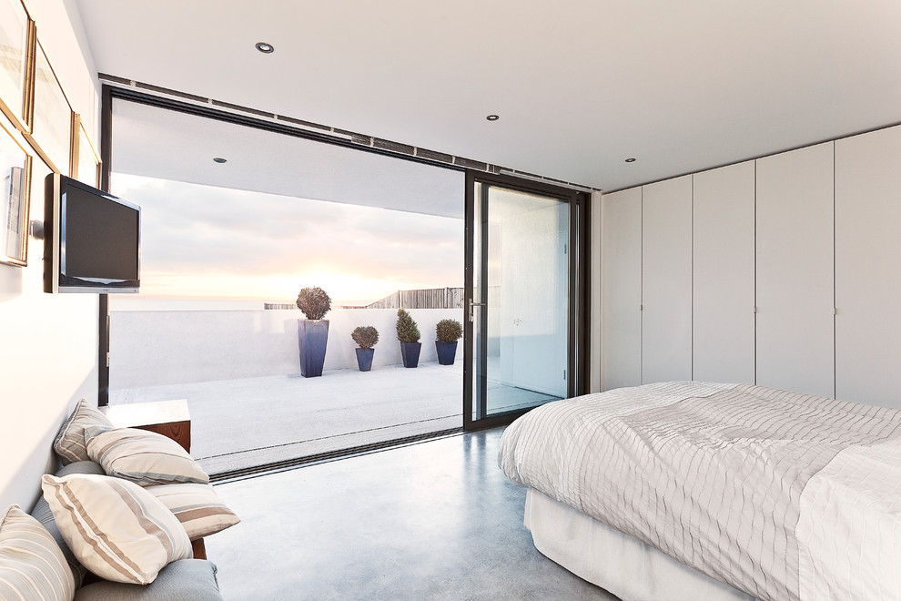 Пример оригинального дизайна: спальня в современном стиле с бетонным полом и телевизором