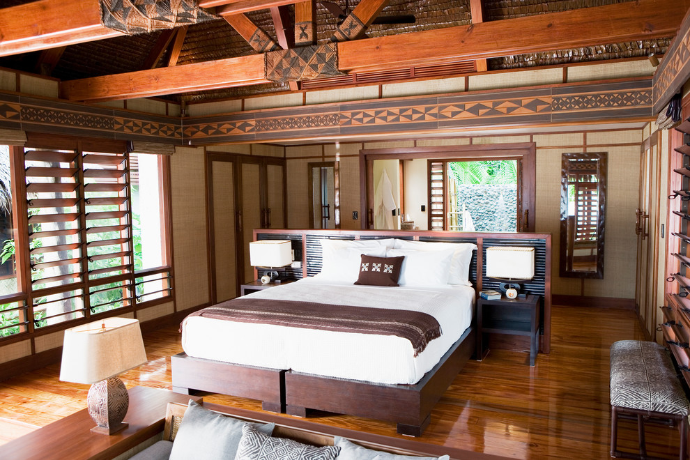 Ejemplo de habitación de invitados exótica de tamaño medio con suelo de madera en tonos medios