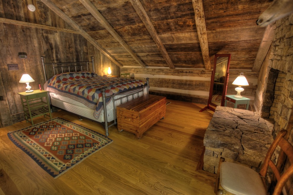 Стильный дизайн: хозяйская спальня среднего размера в стиле рустика с коричневыми стенами, светлым паркетным полом, стандартным камином и фасадом камина из камня - последний тренд