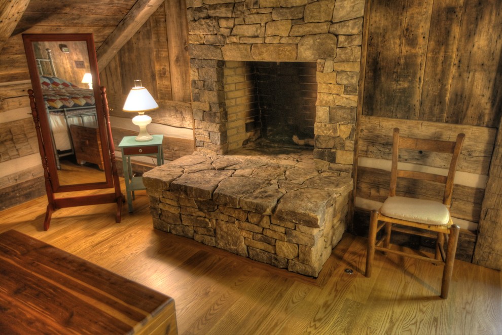 Medium sized rustic master bedroom in Other with brown walls, light hardwood flooring, a standard fireplace and a stone fireplace surround.