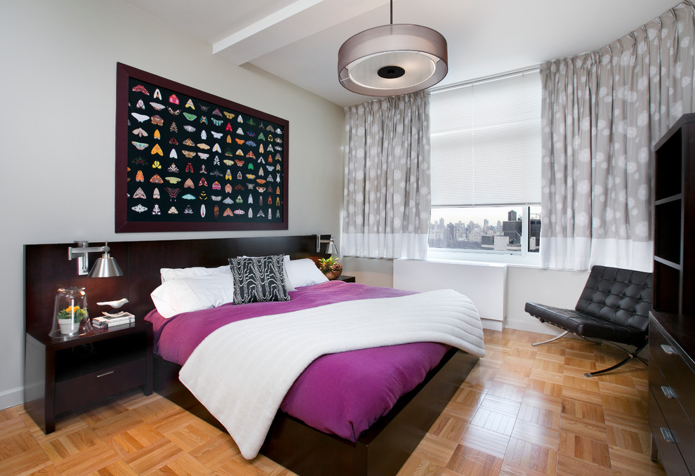 Modelo de habitación de invitados actual de tamaño medio sin chimenea con paredes grises y suelo de madera clara
