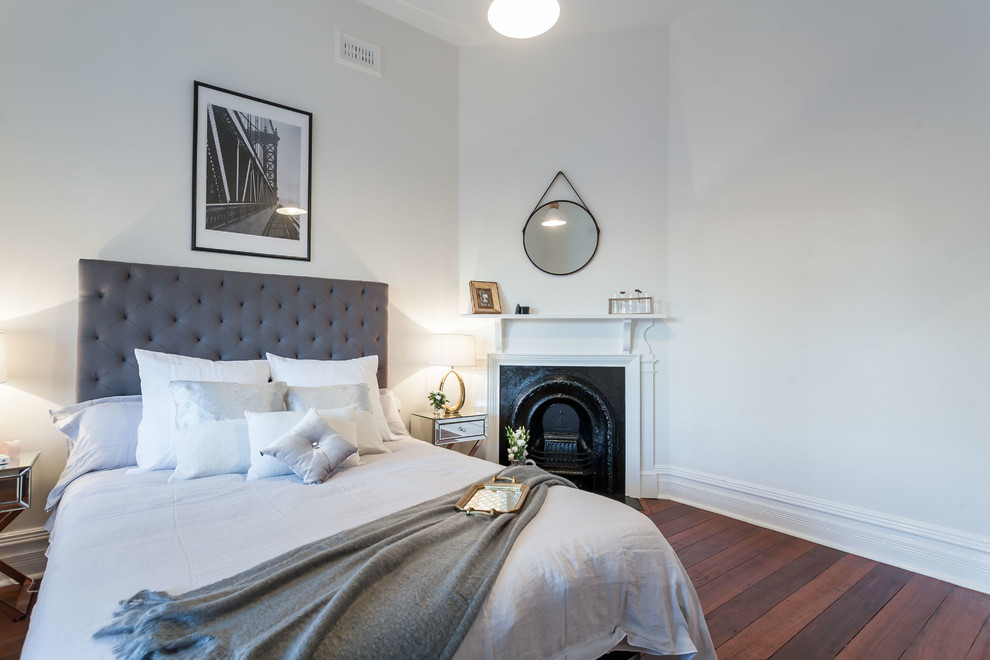 Idées déco pour une chambre classique avec un mur blanc, un sol en bois brun, une cheminée standard et un manteau de cheminée en pierre.