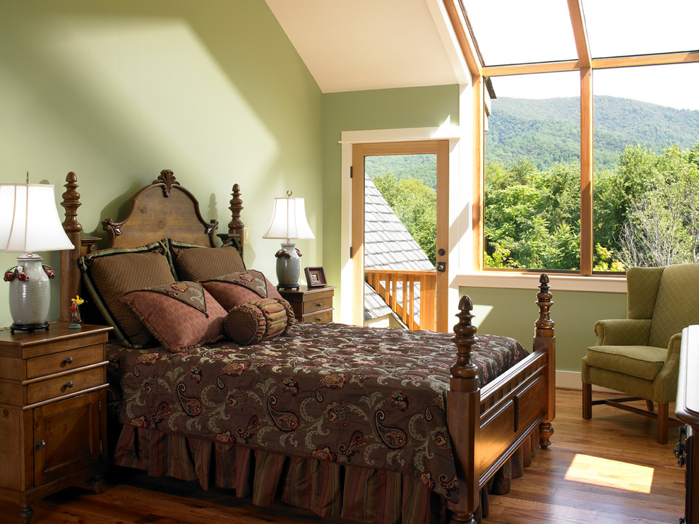 Inspiration för klassiska sovrum, med gröna väggar, mellanmörkt trägolv och brunt golv