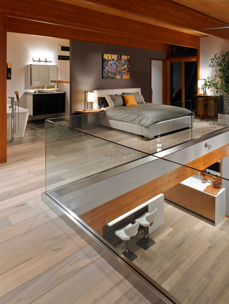 Ejemplo de dormitorio tipo loft contemporáneo de tamaño medio con paredes marrones y suelo de madera clara