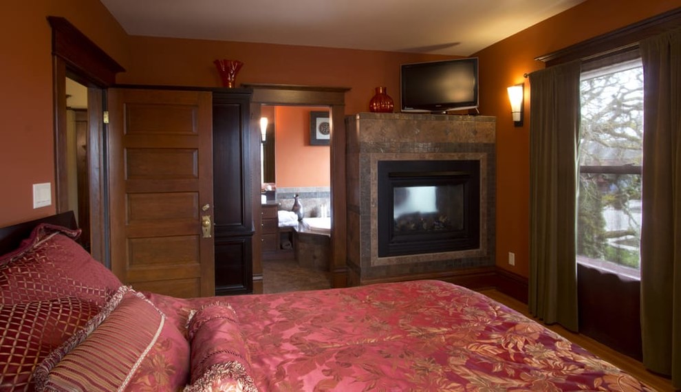 Пример оригинального дизайна: большая хозяйская спальня в стиле кантри с оранжевыми стенами, светлым паркетным полом, двусторонним камином и фасадом камина из плитки