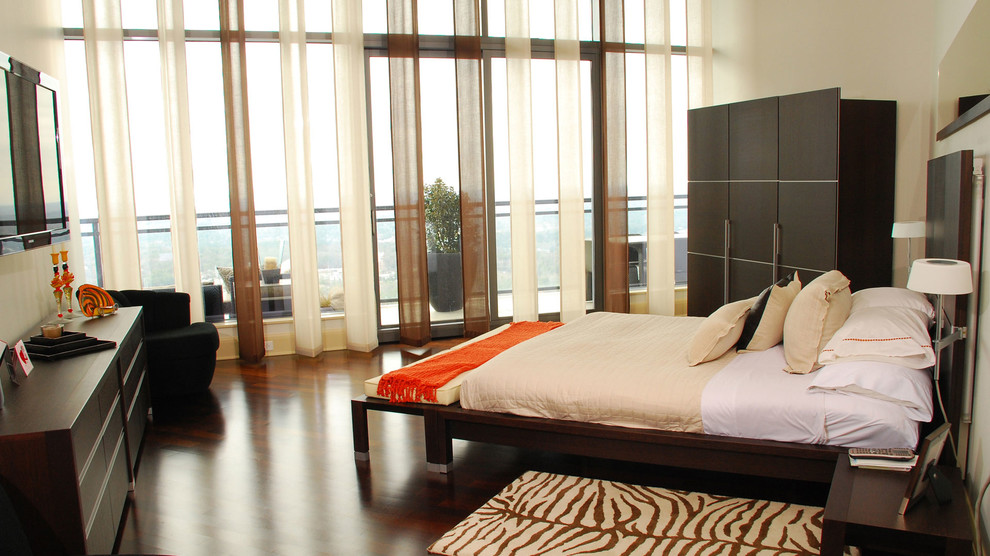 На фото: большая хозяйская спальня в современном стиле с бежевыми стенами и темным паркетным полом с