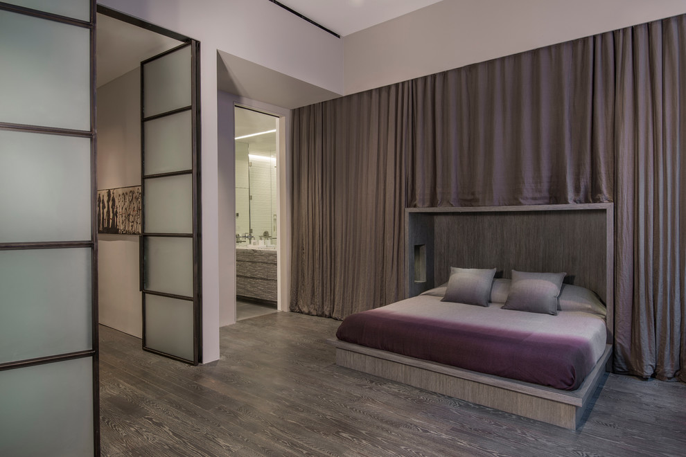 Ejemplo de dormitorio tipo loft minimalista grande sin chimenea con paredes grises, suelo de madera en tonos medios y suelo marrón