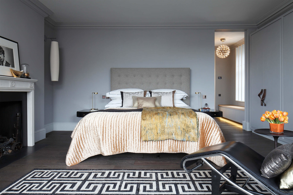 Eclectic grey and brown and grey and silver bedroom in London with grey walls, dark hardwood flooring, a standard fireplace and brown floors.