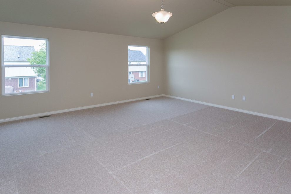 This is an example of a large contemporary master bedroom in Detroit with beige walls, carpet and no fireplace.