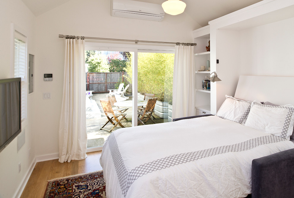 Diseño de dormitorio televisión tradicional pequeño con paredes blancas y suelo de madera en tonos medios