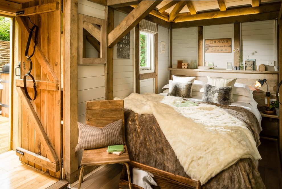Imagen de dormitorio principal rústico pequeño con paredes blancas, suelo de madera clara y suelo beige