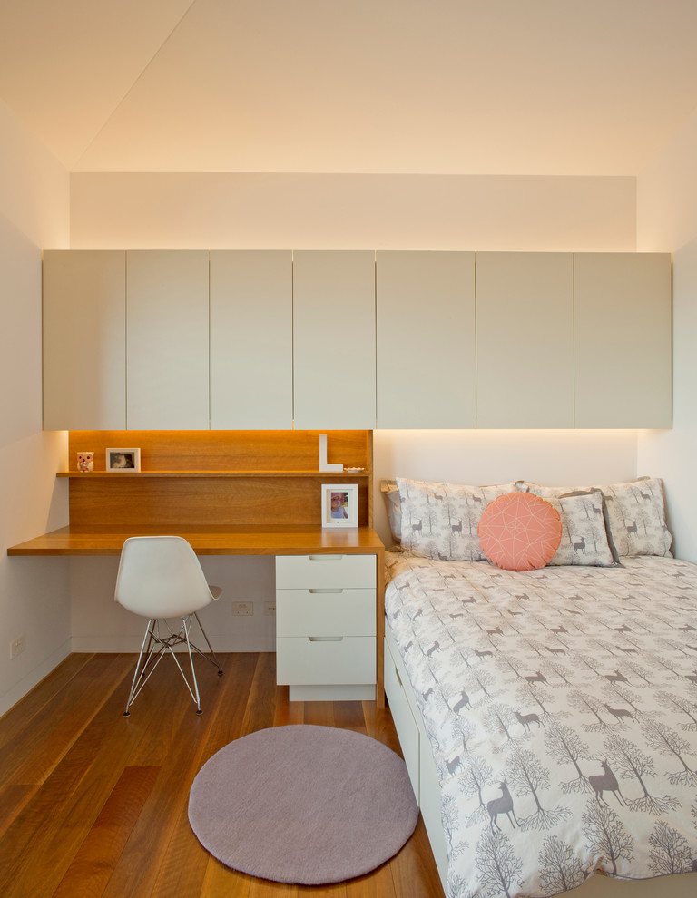 Foto di una camera da letto design con pareti bianche, pavimento in legno massello medio e angolo studio