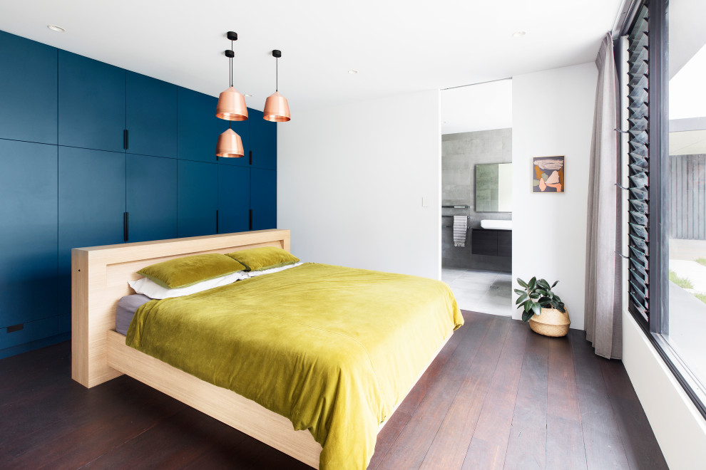 Modelo de dormitorio principal minimalista con suelo de madera oscura, paredes blancas y suelo marrón