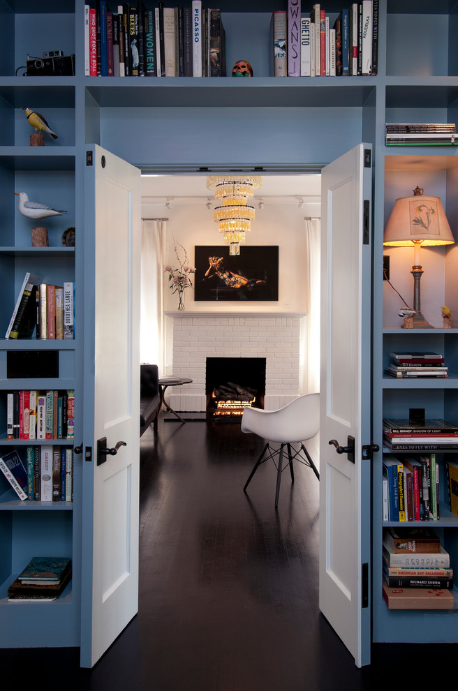 Bild på ett litet eklektiskt gästrum, med blå väggar, mörkt trägolv, en standard öppen spis och en spiselkrans i tegelsten