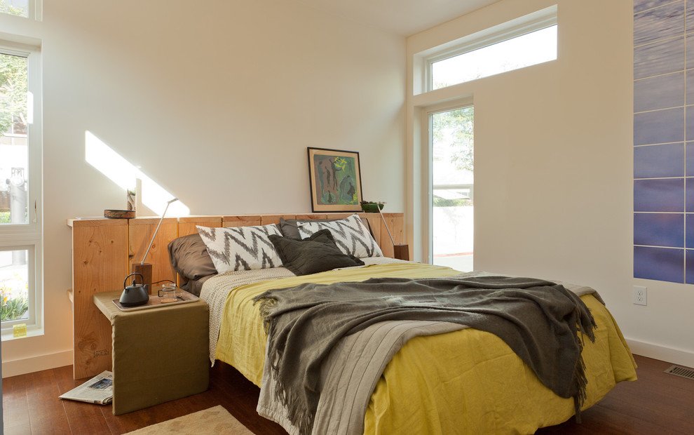 Diseño de dormitorio principal moderno sin chimenea con paredes blancas y suelo de madera en tonos medios
