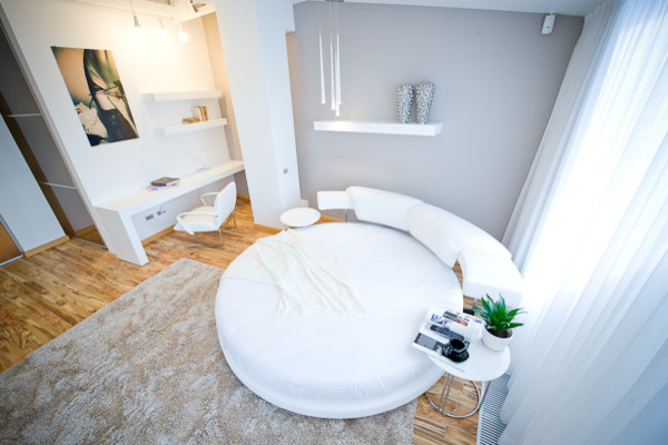 Ejemplo de dormitorio tipo loft contemporáneo grande con paredes blancas y suelo de madera clara